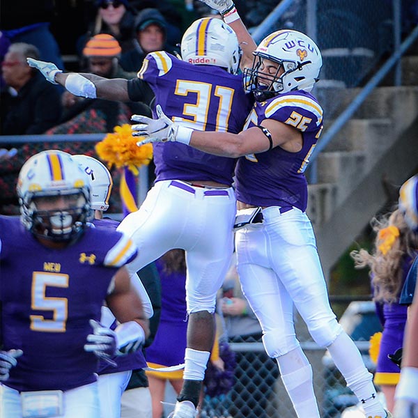 WCU football Players jumping in the air to celebrate a touchdown