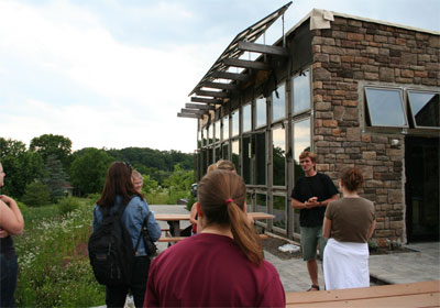 students and a teacher in front of a passive solar building