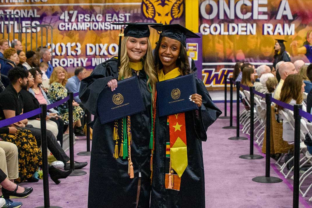 2 female students holding degrees