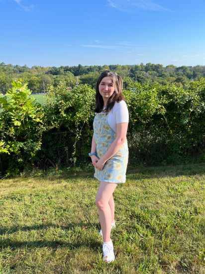 Chloé standing in a vinyard with the greenery and blue sky behind her