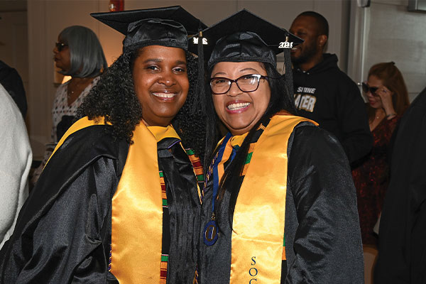 2 WCU students with big smiles in their graduation cap and gown