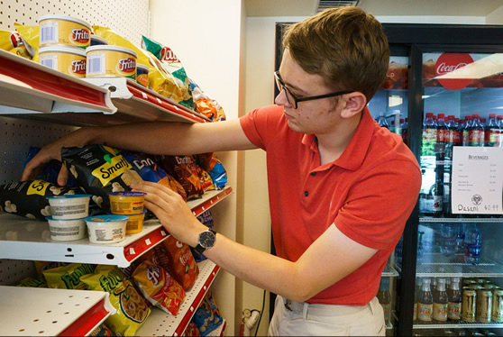WCU student stocks the shelf at Ram Shop 