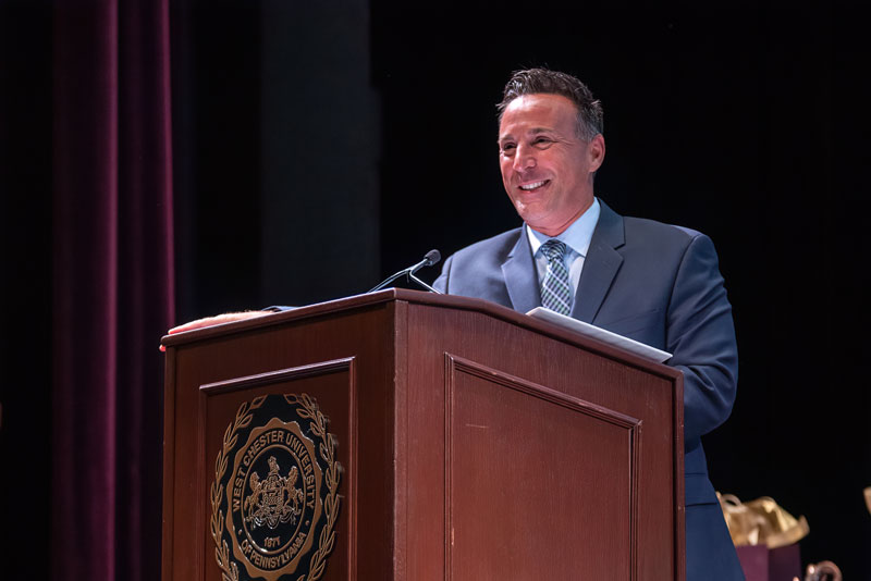 A gentleman behind a podium speaking into a microphone